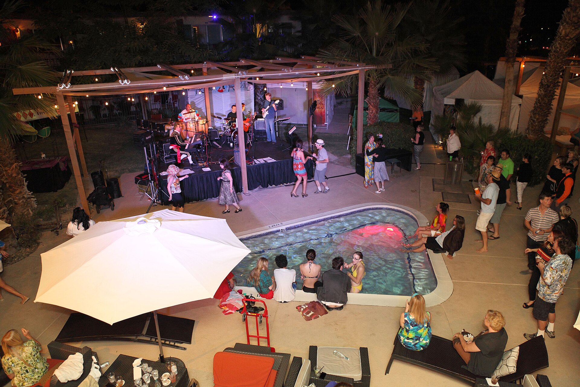 Resort pool party at night with a crowd and live music